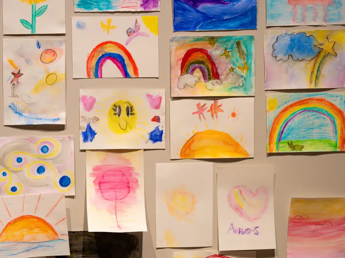 Lots of colourful children's drawings on a wall